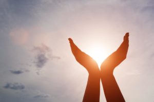 Raised hands catching sun